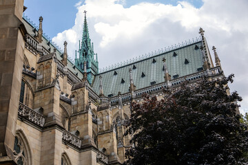 Linz, Austria, 27 August 2021: Facade of medieval catholic stone gothic New Cathedral of Immaculate Conception with arch, old town street at sunny summer day, lancet windows and carved statues