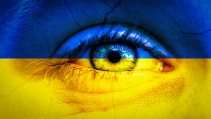 War in Ukraine background - Close-up of child's eye with tears and cracks, in the colors of Ukrainian flag