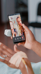Young woman in bed talking to family on video call, using mobile phone for remote communication. Sick patient using online video conference to talk to relatives in hospital ward.