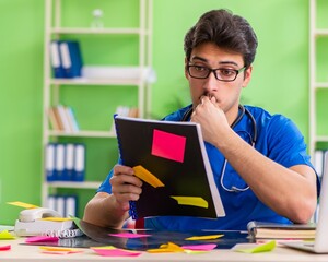 Young doctor sitting in hospital with many conflicting prioritie