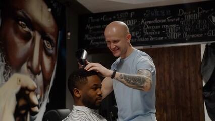 The hairdresser adjusts the peignoir of the Afro-American guy. Tolerance