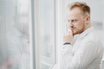 portrait of a young successful man of European appearance, a businessman in a white shirt. Intellectual activity.