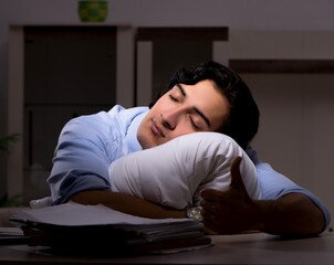 Obraz premium The young handsome employee and too much work in the office