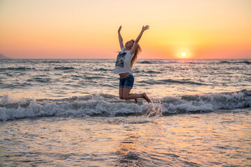 Young woman jumping on beach at sunset