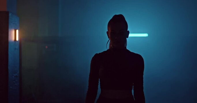Silhouette, a girl athlete walks through a dark room, there is smoke around. Beautiful girl goes to training in a fight club, a serious look on her face. 4k, ProRes