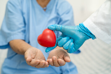 Doctor give red heart to Asian senior or elderly old lady woman patient, healthy strong medical concept