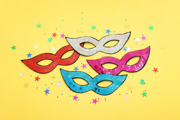 Holidays image of carnival party sequins masks over yellow background. view from above