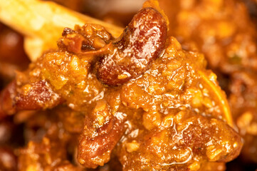 Stewed beans with meat in a small pot. A traditional rustic dish. Close-up, selective focus.