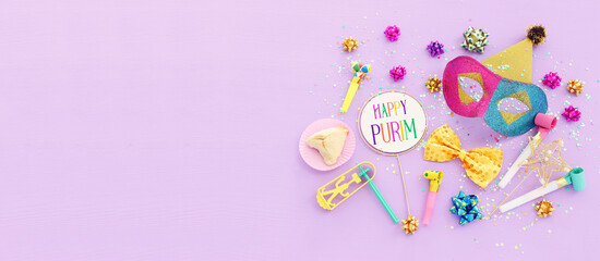 Purim celebration concept (jewish carnival holiday) over purple wooden background