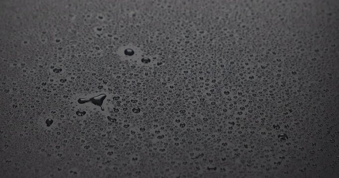 Raindrops falling on a black surface. The beginning of the rain