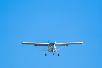 Small cessna aircraft monoplane flying head-on in a clear blue sky before landing on Sabadell airport.