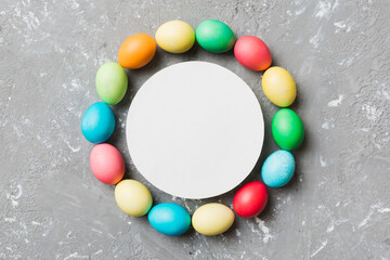 round frame multicolored Easter eggs with white blank paper on a brown background, close-up, space for text, blank for design, selective focus, tinted image