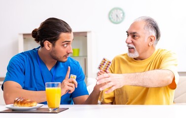 Young male doctor visiting old patient at home