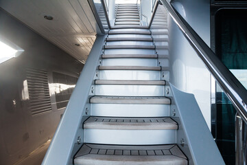 Access to the next floor of the yacht with a wooden staircase, railings and a closing hatch. Internal staircase on the yacht with handrails. Yacht interior with ladder.