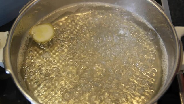 Simmering sugar syrup and a slice of lemon in a pot