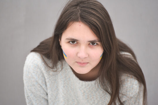 Portrait of Ukrainian girl with national flag on cheek, patriot of Ukraine teen girl. 