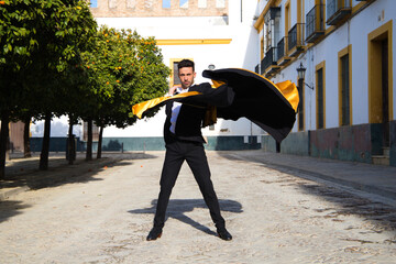 Portrait of young and handsome gipsy man, dressed in black and red shoes dancing with a black and...