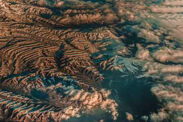 Aerial view from the plane of hills snow and mountains landscape with shadows of sunlight and clouds covered beautifully. Above the clouds, Snow capped mountain, No focus, specifically.