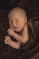 The newborn sleeps in a brown blanket. Happy childhood. Child care. Child