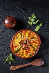 Couscous with meat and vegetables, traditional Moroccan food, shot from the top on a dark background with fresh herbs and spices, a flat lay