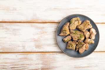 Stewed turkey fillet with garlic on white wooden background. top view, copy space.