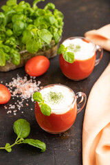 Tomato juice with basil and himalayan salt in glass on a black background. Side view, selective focus.