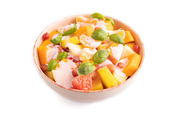 Vegetarian fruit salad of yogurt pumpkin, tangerine, basil microgreen isolated on white, side view, close up.