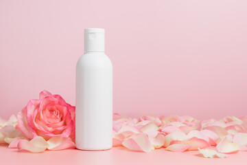 Obraz na płótnie Canvas White unbranded mockup bottle of body lotion or shampoo with roses and petals, bottle for logo or design, natural cosmetic
