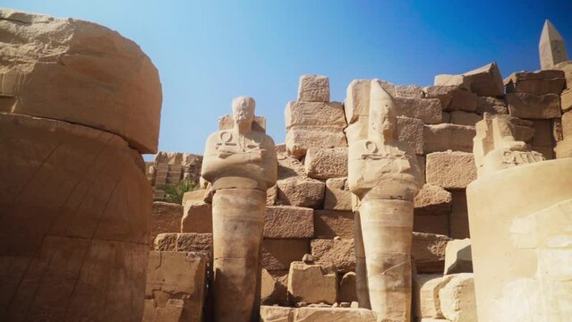 Large statues between massive square rocks outside the Karnak Temple in Luxor, Egypt. 
Static shot.