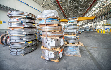 Aluminum strips wound on coils, industrial background, warehouse with high ceiling.