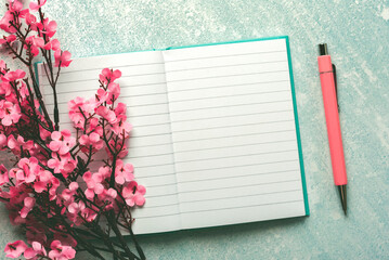Naklejka premium Top view of blank journal open with copy space, pink pen and almond blossoms