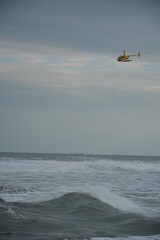 Fototapeta premium helicopter soaring over the waves and the beach