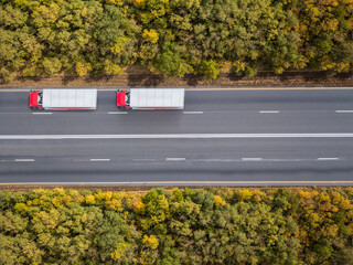 Aerial top down shot of highway with truck trailer and the car.