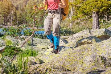 Hiker wears waterproof gaiters over trekking boots walking with hiking sticks. Clothing and...