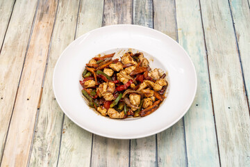Dish of wok chicken with soy sauce, chopped red and green peppers, onion and carrots