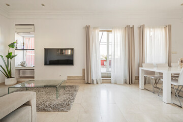 Living room with access to terrace with cream marble floors, wall-mounted TV and gray carpet in short-term rental apartment