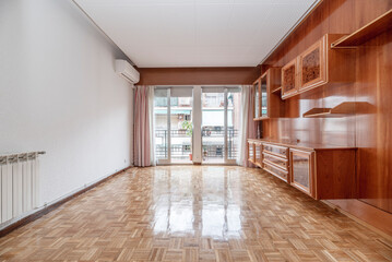 Fototapeta premium Living room with white aluminum radiators, air conditioning unit, wooden bookcase mural on one wall and oak parquet flooring