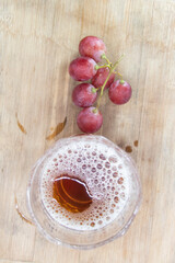 glass of wine with grapes isolated on wooden background, top view