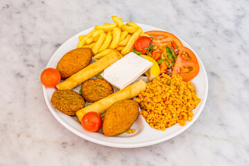 Turkish traditional menu plate with falafel, croquettes, cheese strips, french fries, salad and orange lentil stew