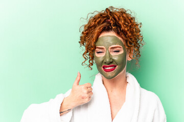 Young red hair woman with a facial aloe vera mask after a bath isolated smiling and raising thumb up