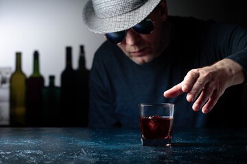 Man in the hat is drinking whiskey.