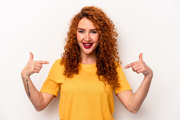 Young ginger caucasian woman isolated on white background surprised pointing with finger, smiling broadly.