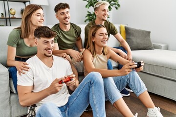 Group of young friends smiling happy playing video game at home.