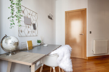 Study table with globe of the world with white leather chair and wooden floors