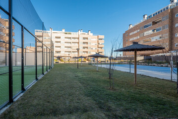 Common areas of an urbanization with paddle tennis courts and swimming pool with straw umbrellas