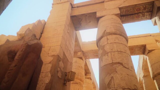 Tall pillars and pylons in the Karnak Temple, Luxor Egypt. Intricate carved drawings and hieroglyphs adorning the pillars. 
Slow slide movement sideways. 