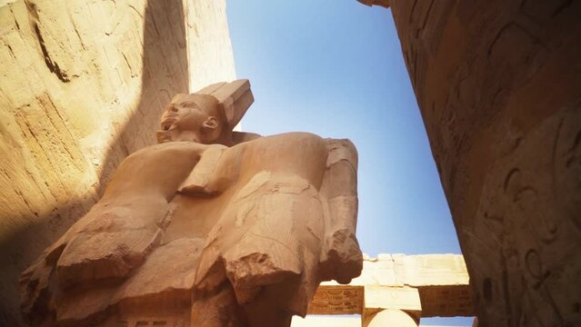 Statue of King Ramses in the Karnak Temple, Luxor Egypt. 
Slow camera rotation from a low angle, backlit by the sun. 