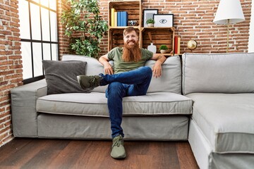 Obraz premium Young redhead man smiling confident sitting on sofa at home