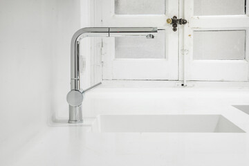 90 degree angle faucet set into a one piece sink with white kitchen countertop
