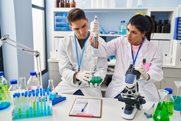 Man and woman scientists partners using pipette at laboratory